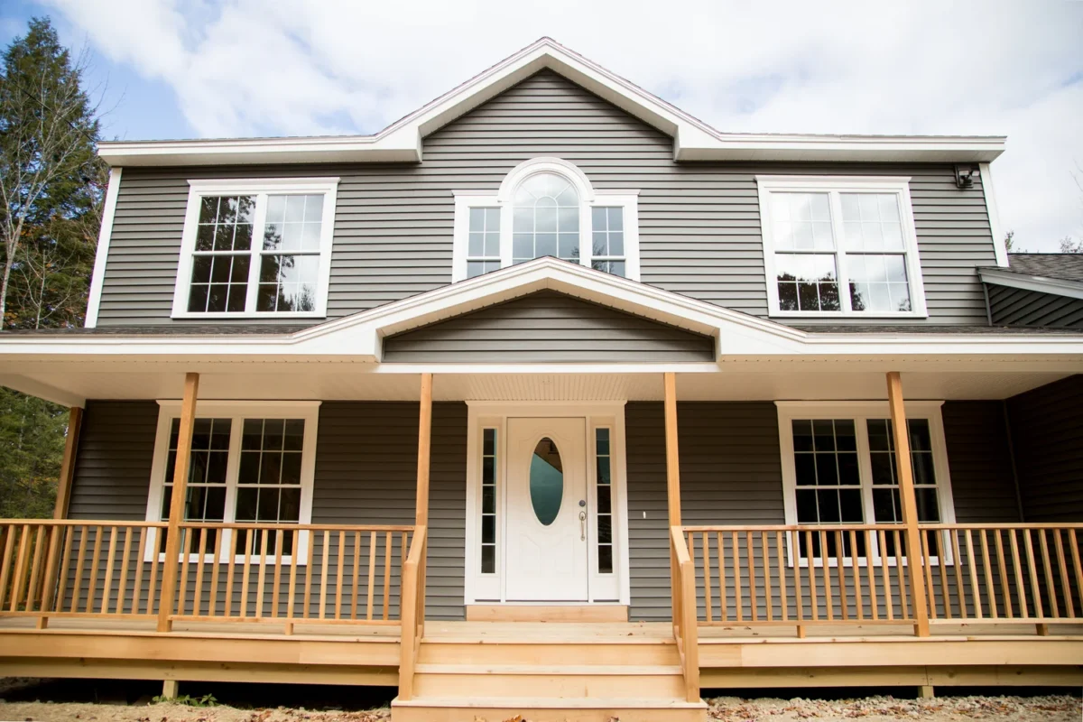 Modern two-story family home featuring gray siding, white accents, a spacious covered porch, and symmetrical front elevation.