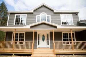 Modern two-story family home featuring gray siding, white accents, a spacious covered porch, and symmetrical front elevation.